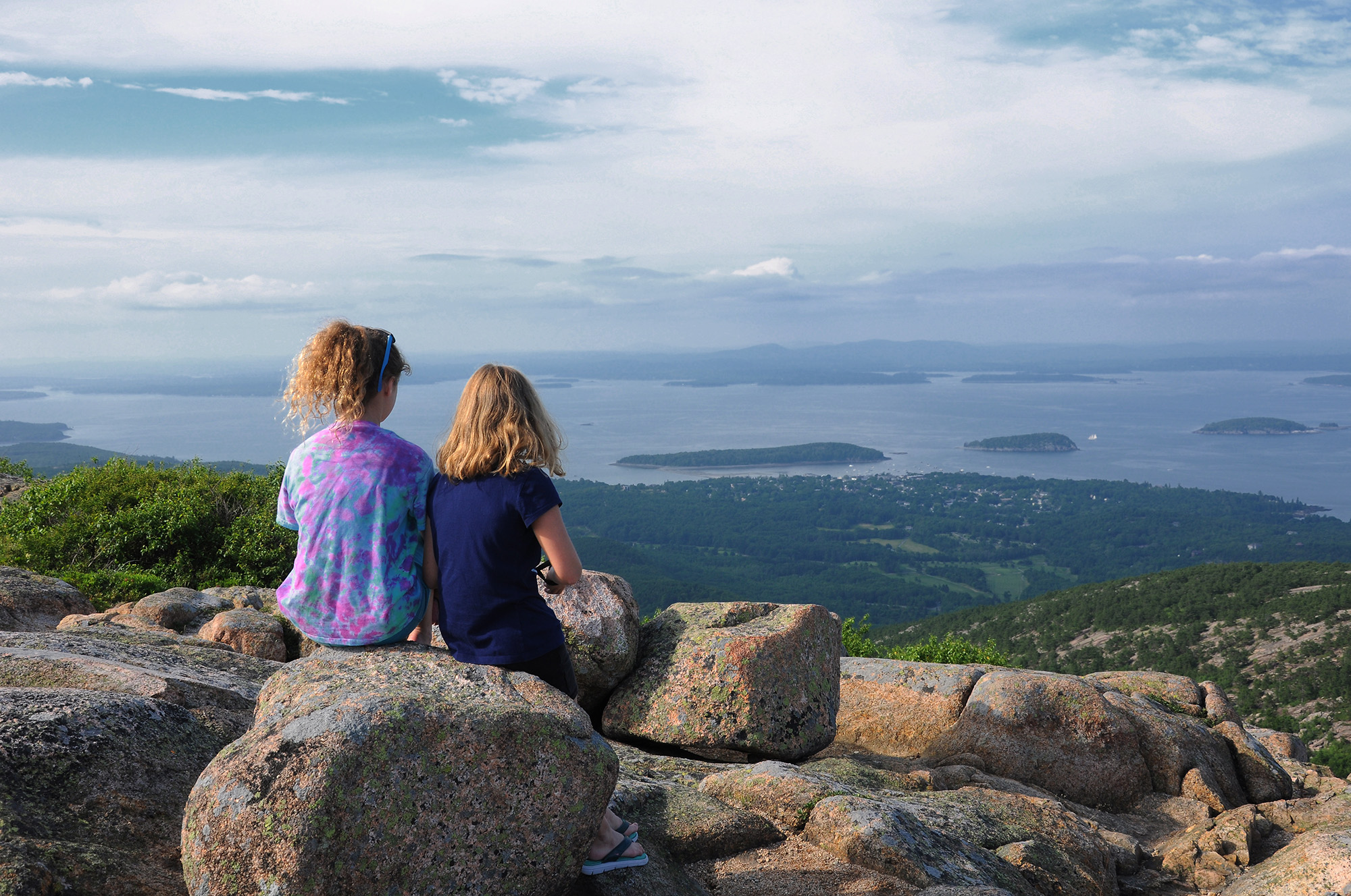 Photo of two girls sitting on rock at top of Cadillac Mountain