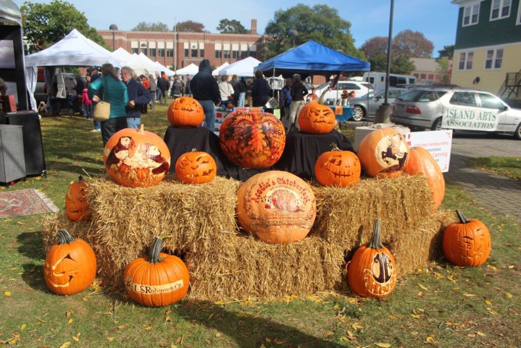 Carved and decorated pumpkins displayed on bales of hay.